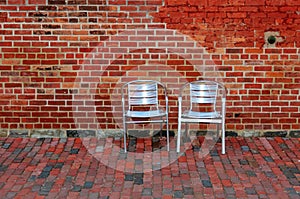 Red Brick Wall and Two Metal Chairs