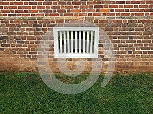 Red brick wall with white window and green grass