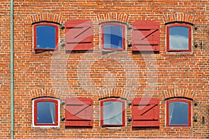 Red brick wall with windows and shutters