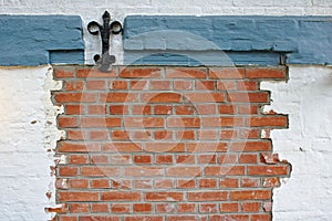 Red brick wall with wrought-iron decoration, partly plastered with white and blue plaster