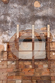 Red brick and white plaster exterior wall with barred window, vertical