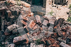Red bricks of destroyed house by war, hurricane or other natural catastrophe or disaster, ruins of abandoned dwelling