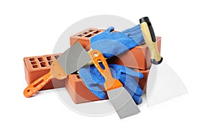 Red bricks, gloves and trowels on white background
