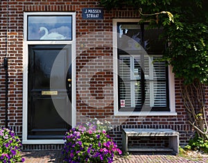 Red bricks house facade with window, door, bench and flowers Naarden Netherland