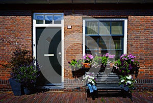 Red bricks house facade with window, door, bench and flowers Naarden Netherland