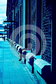 Red bricks houses and pedestrial road, defocused people seen from far away. Urban and industrial image. Vertical with