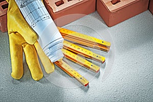 Red bricks protective gloves construction plans wooden meter on