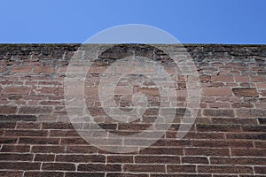 Red brickstone wall under blue sky (low angle view), use: background, wallpaper, texture