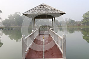 Red bridge connect between white pavilion in mash and land.