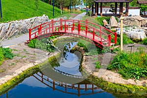 Red bridge and gazebo by pond in Japanese garden