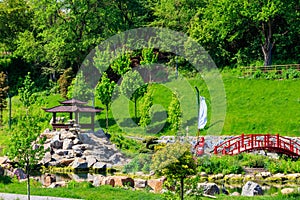 Red bridge and gazebo by pond in Japanese garden