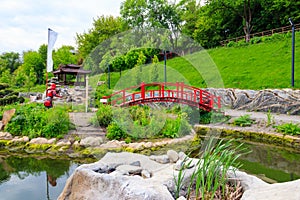 Red bridge and gazebo by pond in Japanese garden