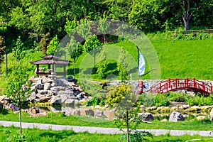 Red bridge and gazebo by pond in Japanese garden