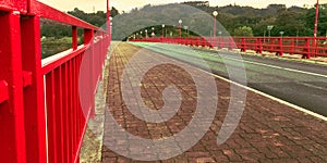 red bridge with streetlights across lake with forest in background