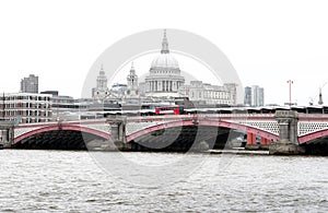 Red British Bus on Blackfriars Bridge with St Paul`s Cathedral and London Skyline