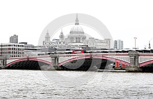 Red British Bus on Blackfriars Bridge with St Paul`s Cathedral and London Skyline photo