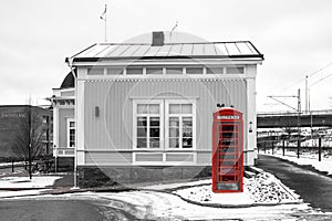 Red British phone box standing by the traditional wooden cottage