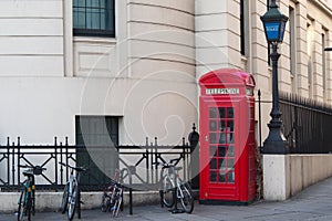Red british telephone booth and some bicycles. London street, no people