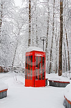 Red British telephone booth used as street library in winter