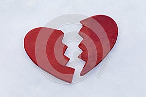 Red broken in half toy heart in the snow, concept or metaphor broken heart, background for Valentine\'s Day