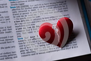 Red broken heart on dictionary love definition. The concept of broken heart, parting, infidelity . Selective focus