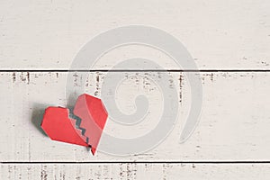 Red broken heart on white wooden background