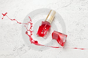 red broken nail polish bottle on marble background, dye color splash and suffusion photo