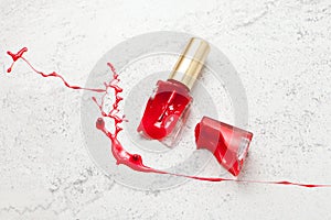 red broken nail polish bottle on marble background, dye color splash and suffusion