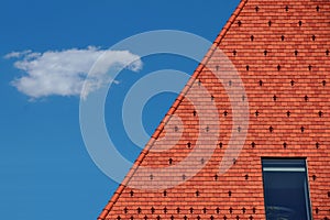 Red and brown clay tile roof. steep slope. glass skylight. bright blue sky with white cloud