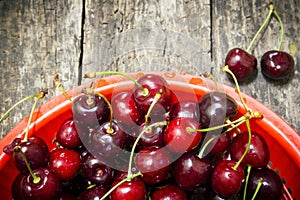 Red bucket scoured rural cherries on a wooden