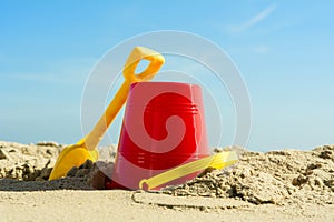 Red Bucket and yellow spade on sandy beach