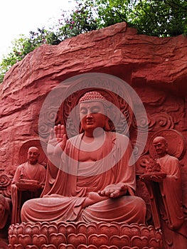A Red Buddha Sculpture with servants