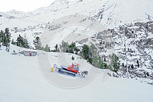 Red bully pisten on snow track for skiers with pine tree