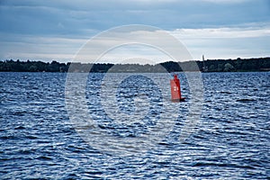 Red buoy drifts in the swell against a blue sky.