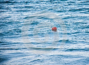 Red buoy floating on the blue sea waves