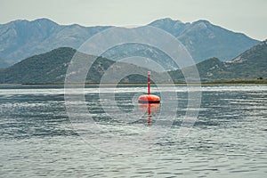 Red buoy floating on lake water surface