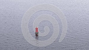 Red buoy floating on rippled water