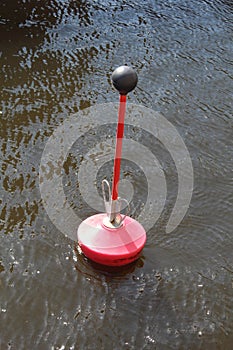 A red buoy floats on the surface of the river