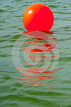 Red buoy on the greenish sea water