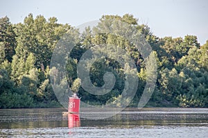 Red buoy on quiet river on summer day.