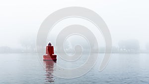 Red buoy in a river in the mist
