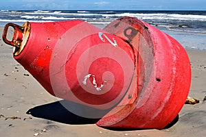 Red buoy washed up on the beach after a hurricane