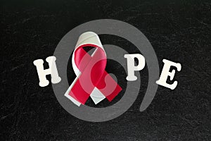 Red or burgundy and white ribbon color isolated on dark black background. Head and neck cancer awareness