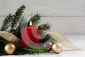 Red burning candle with christmas decoration, fir tree, baubles