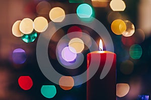 Red burning candle and colourful background