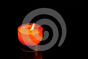 Red burning candle on a glass table