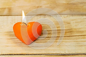 Red burning heart shaped candle with copy space on wooden background