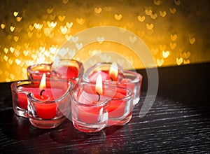 Red burning heart shaped candles on golden hearts bokeh