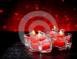 Red burning heart shaped candles on red hearts bokeh