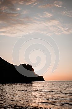 A red burning sunset over the sea with rocky volcanic cliff. Abstract nature summer or spring ocean sea background.
